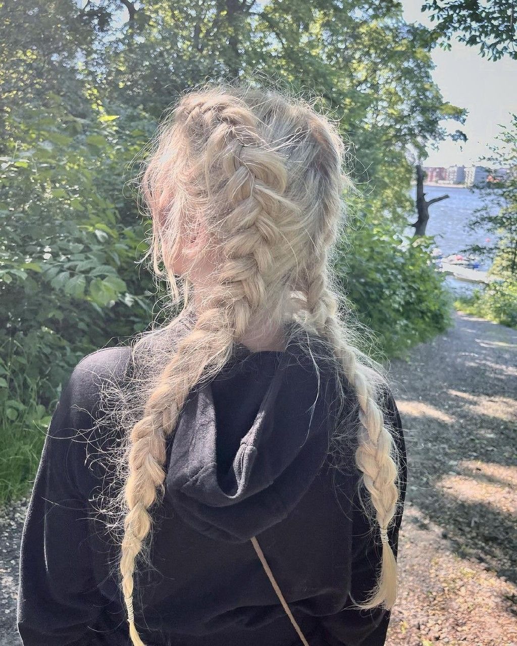 Blonde hair styled in two loose, wavy braids from a back view outdoors.