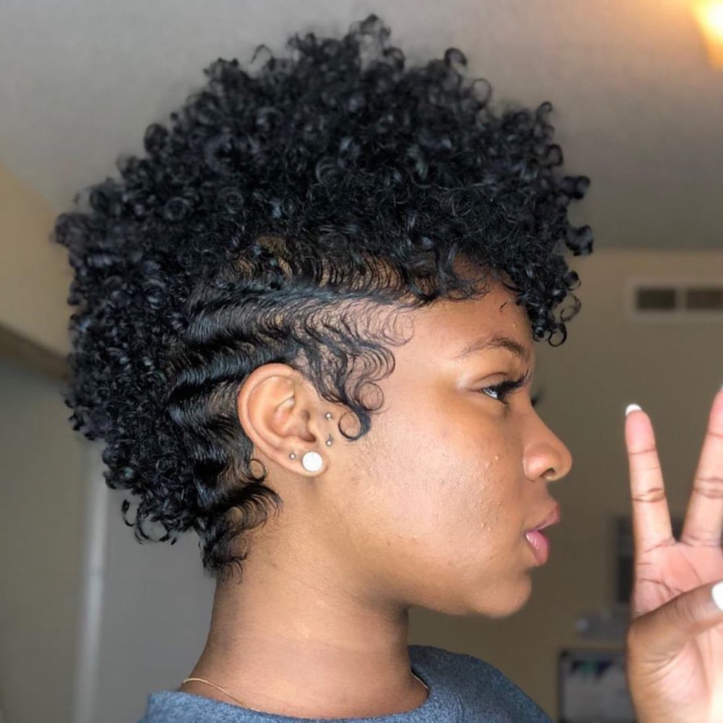 Woman with a mohawk hairstyle featuring tight curls on top and wavy sides.