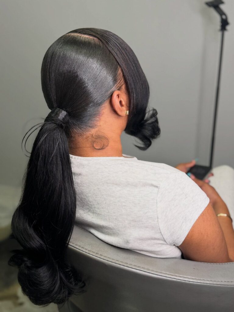 Woman with a sleek low ponytail and polished black hair in a salon.