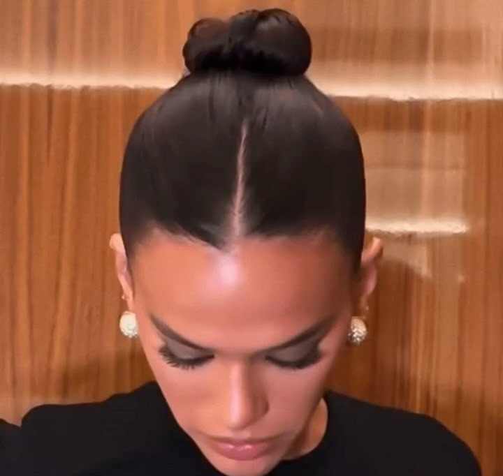 Woman with sleek dark hair styled in a tight high bun and center part.