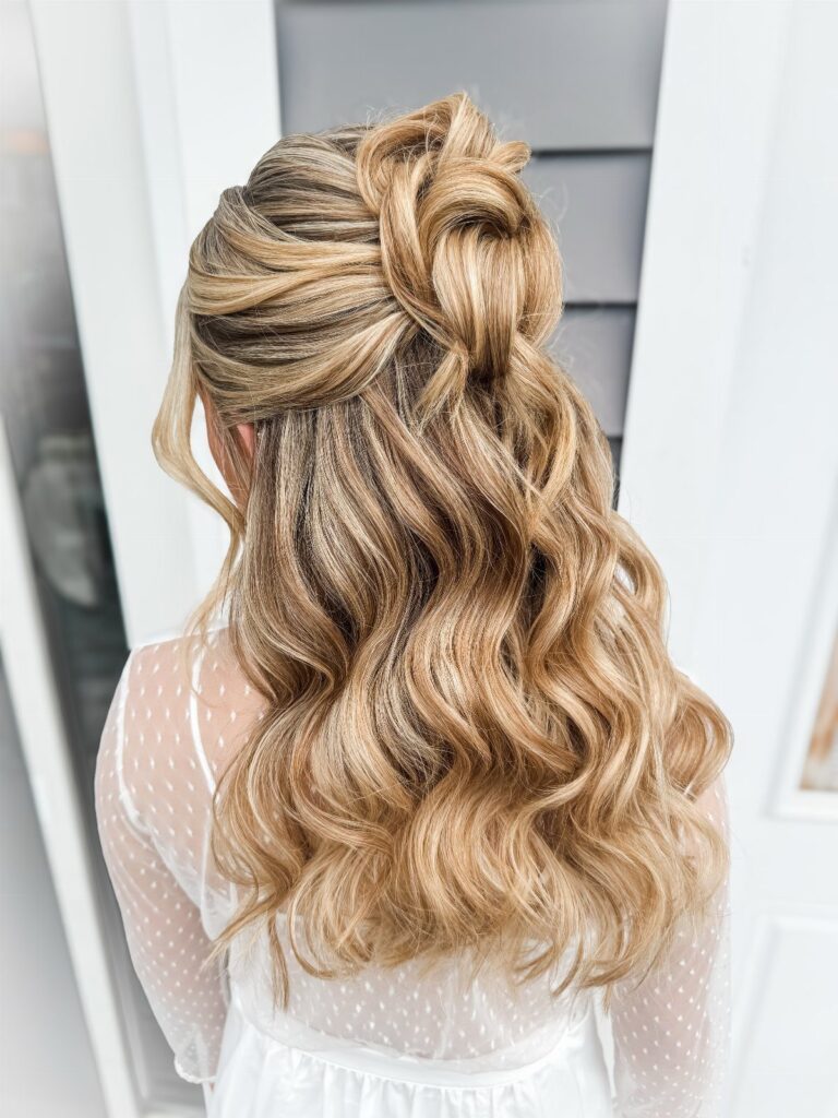 Blonde wavy hair styled in a half-up twisted knot half-updo from behind.
