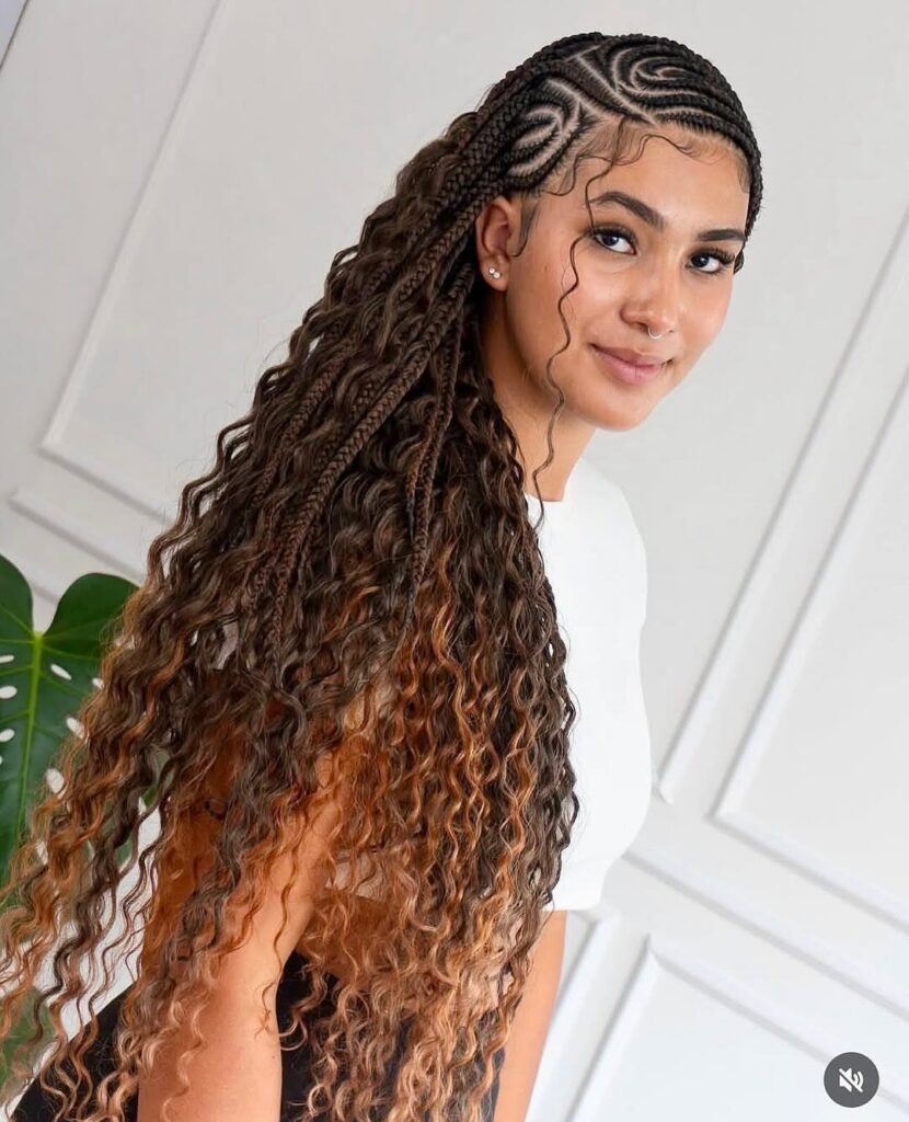Woman with cornrow braids transitioning into long, curly brown hair against white wall.