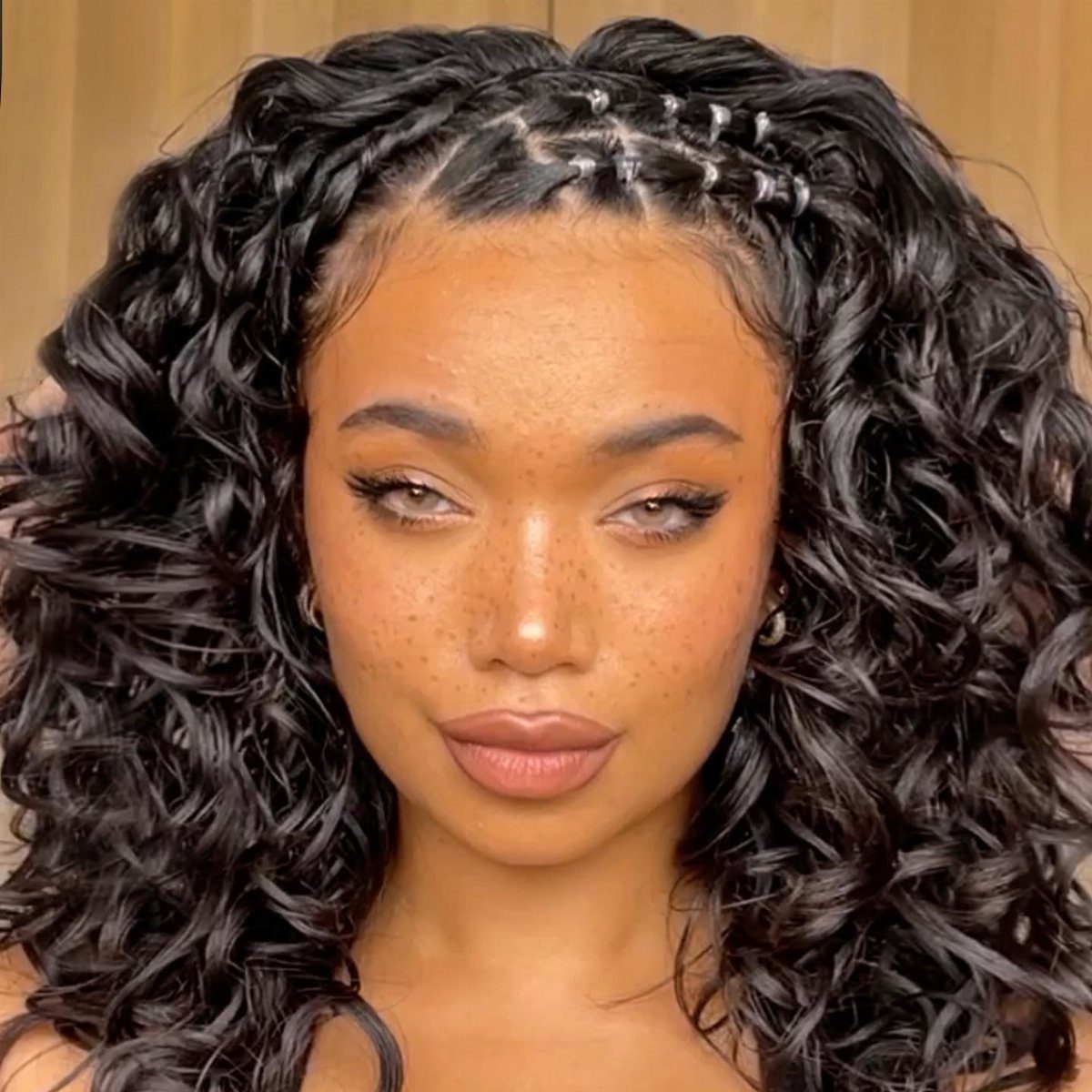 Woman with long black curly hair featuring silver rings in a top braid.