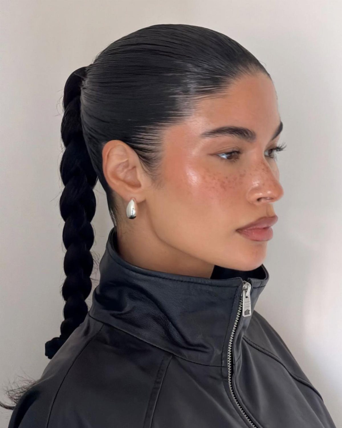 Woman with slicked-back hair styled into a long, dark braided ponytail.