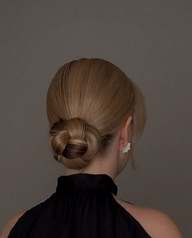 Blonde hair styled into a sleek low bun at the nape of the neck.
