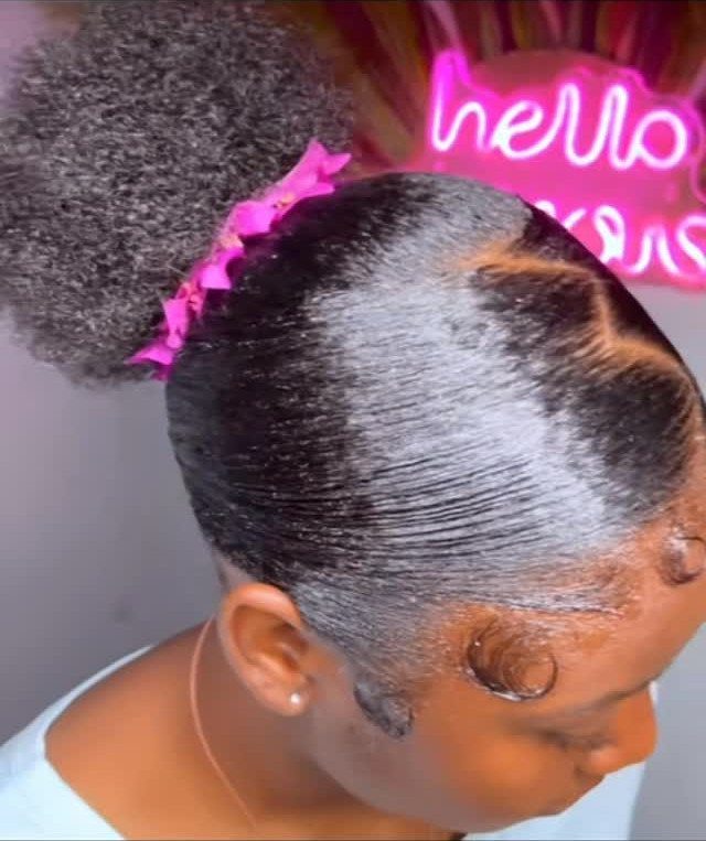 Woman with slicked-back hair and a high afro puff with pink hair tie