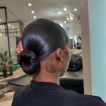Woman with sleek dark hair styled into a smooth, tight low bun.