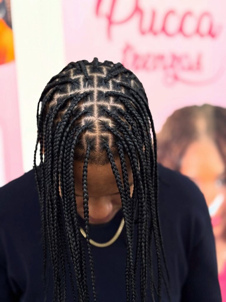 Man with black knotless braids styled in a precise grid pattern on scalp