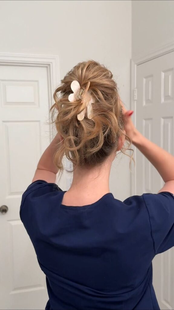 Blonde hair styled in a messy updo secured with a white claw clip.