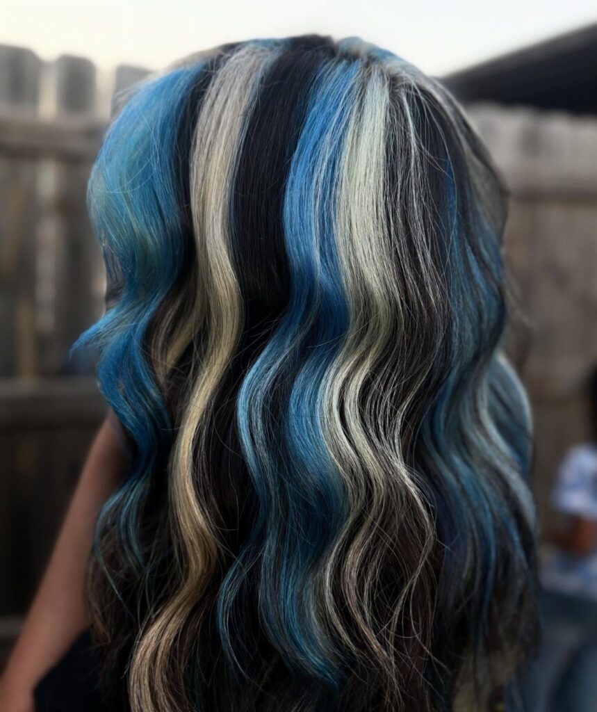 Wavy hair with thick vertical streaks of blue, blonde, and black hair dye.