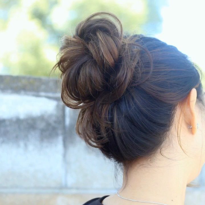 Dark brown hair styled into a high, voluminous twisted bun from behind.