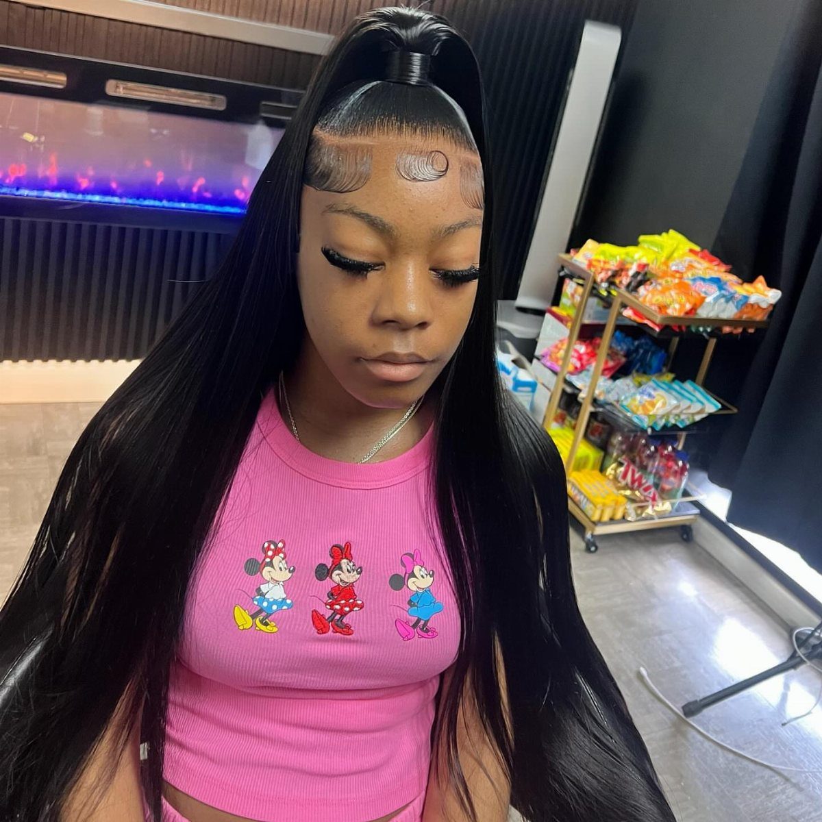 Woman with long straight black hair in a high half-up ponytail wearing pink.