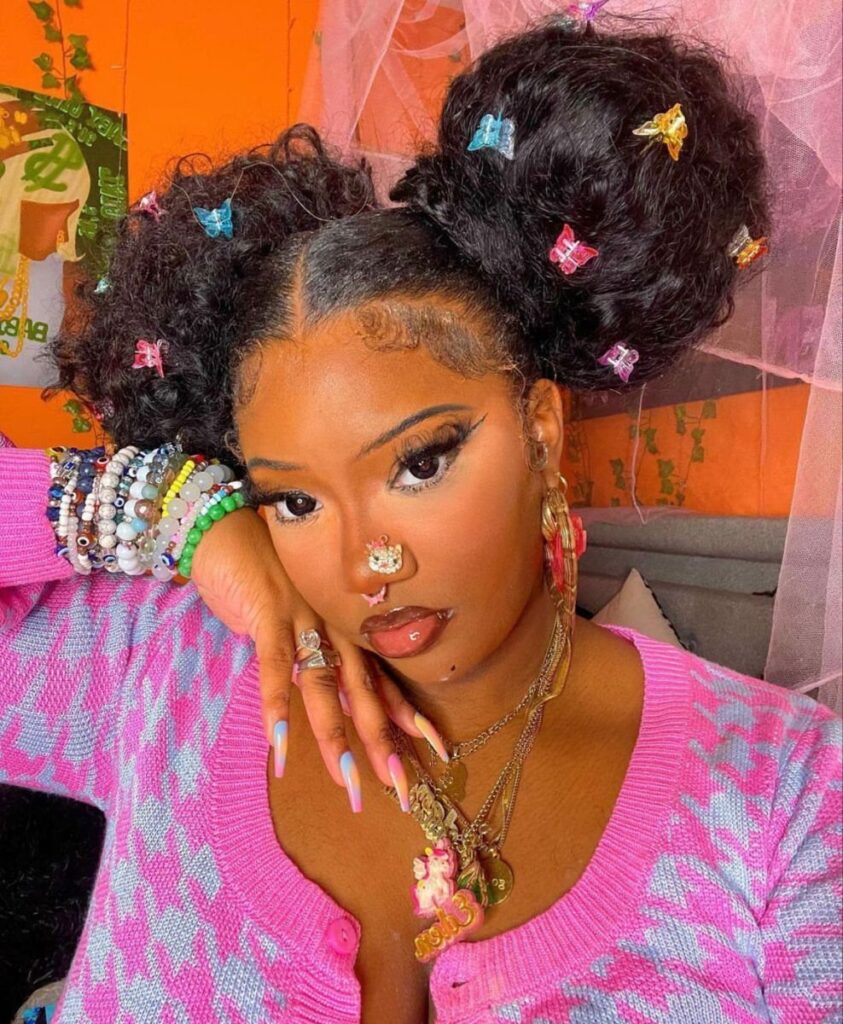 Woman with two high hair puffs decorated with colorful butterfly clips and jewelry.
