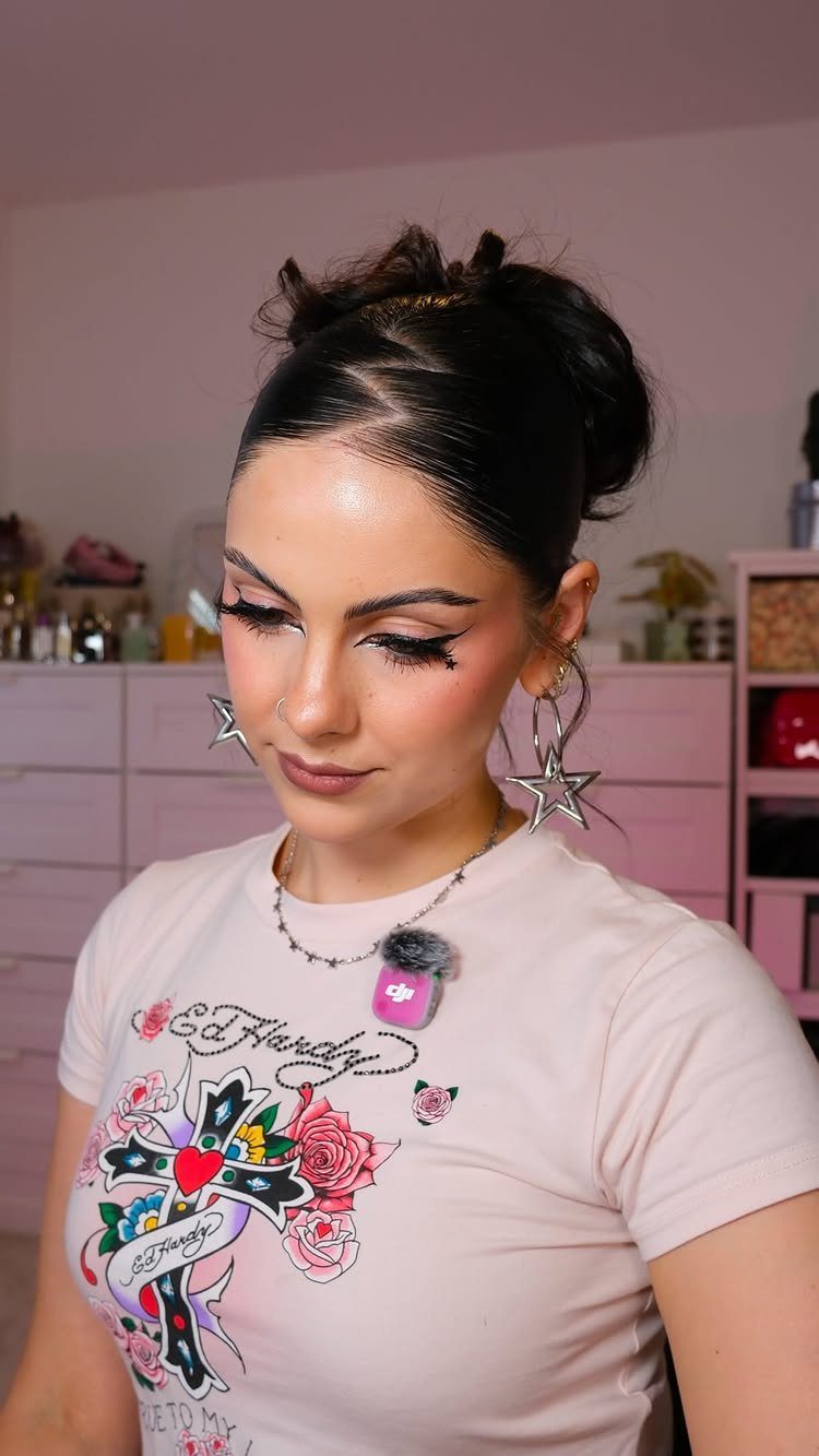 Woman with a slicked-back middle part and a messy bun wearing star earrings.