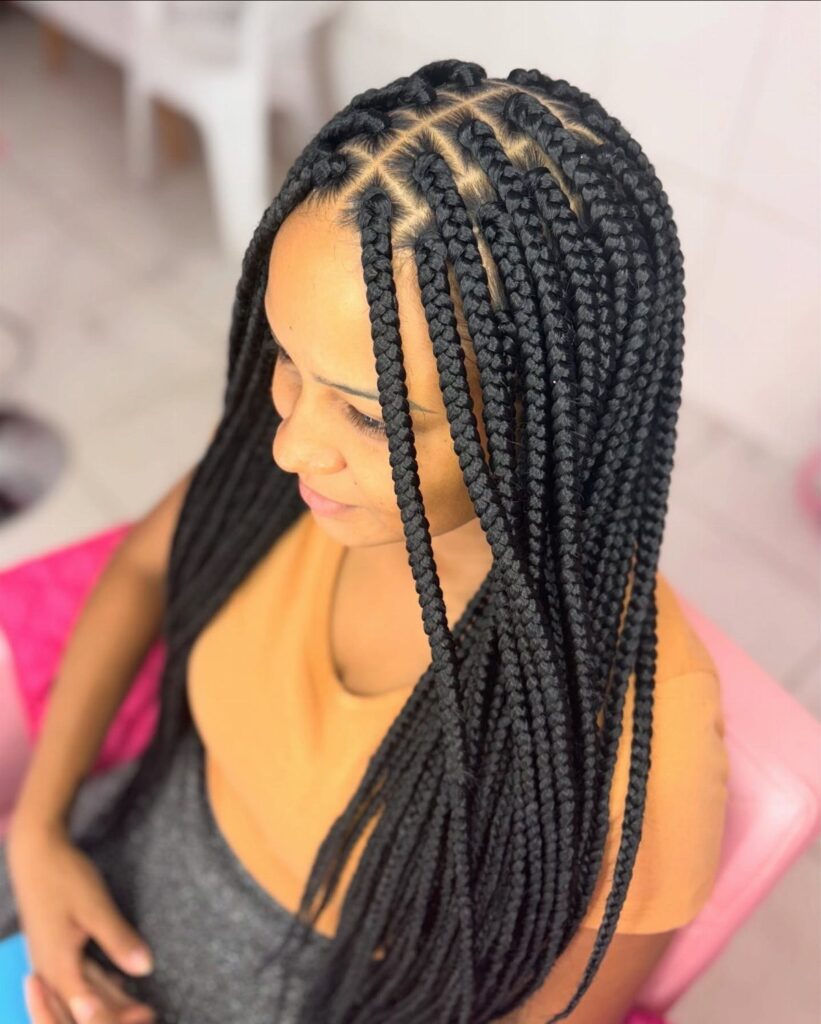 Woman with long black box braids partitioned in square sections on her scalp