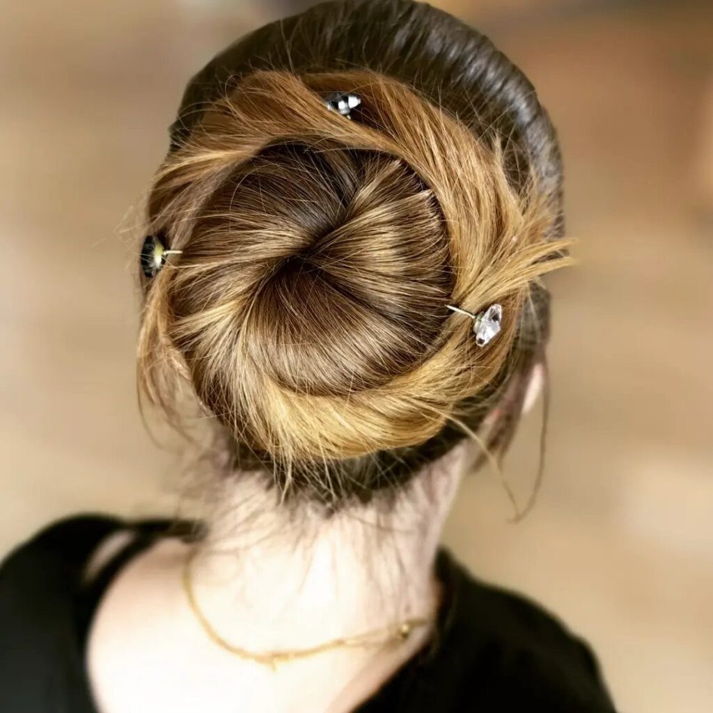 Twisted brown and blonde hair bun adorned with three sparkling jeweled hairpins.