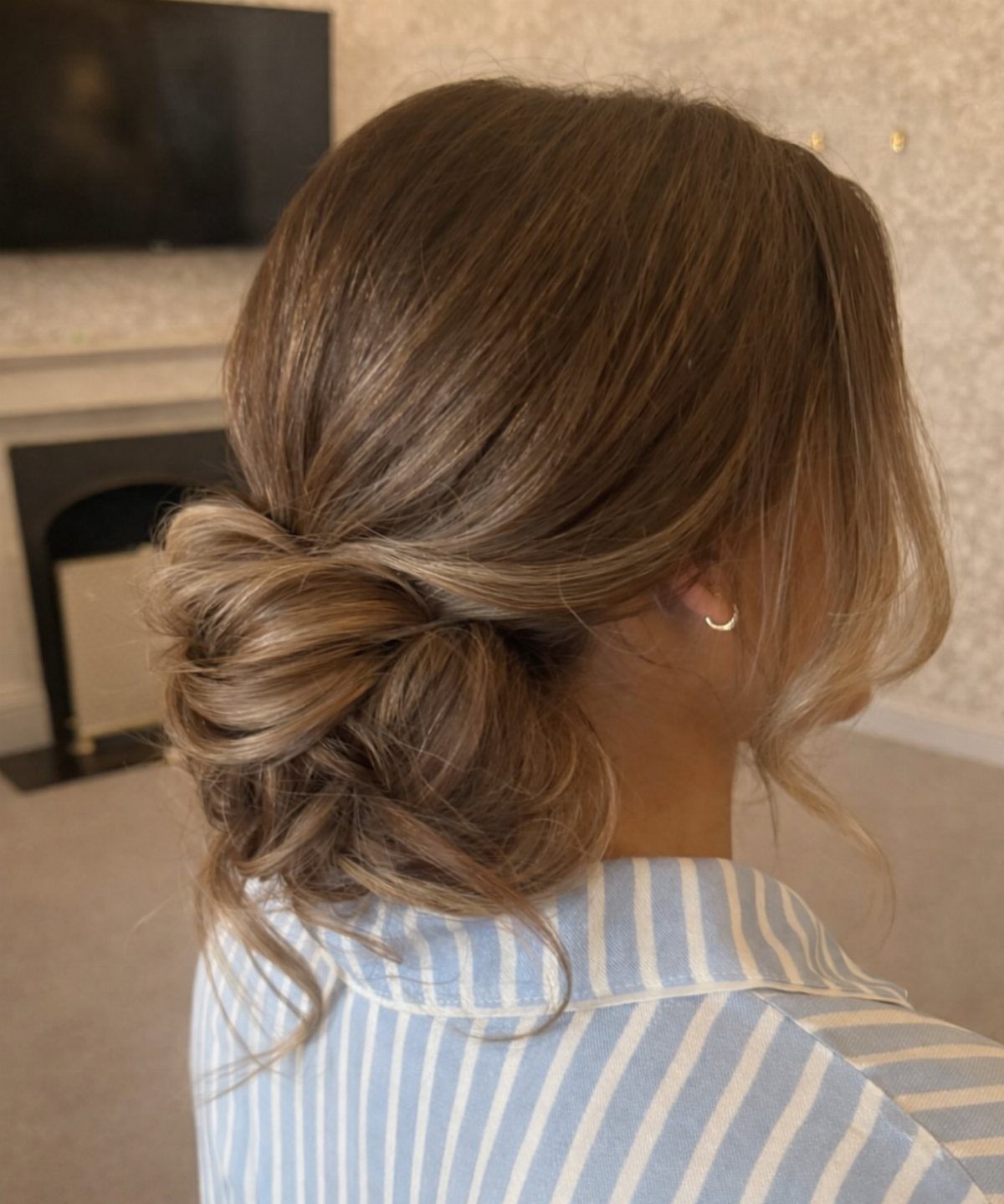 Woman with light brown hair styled in a textured low chignon bun.