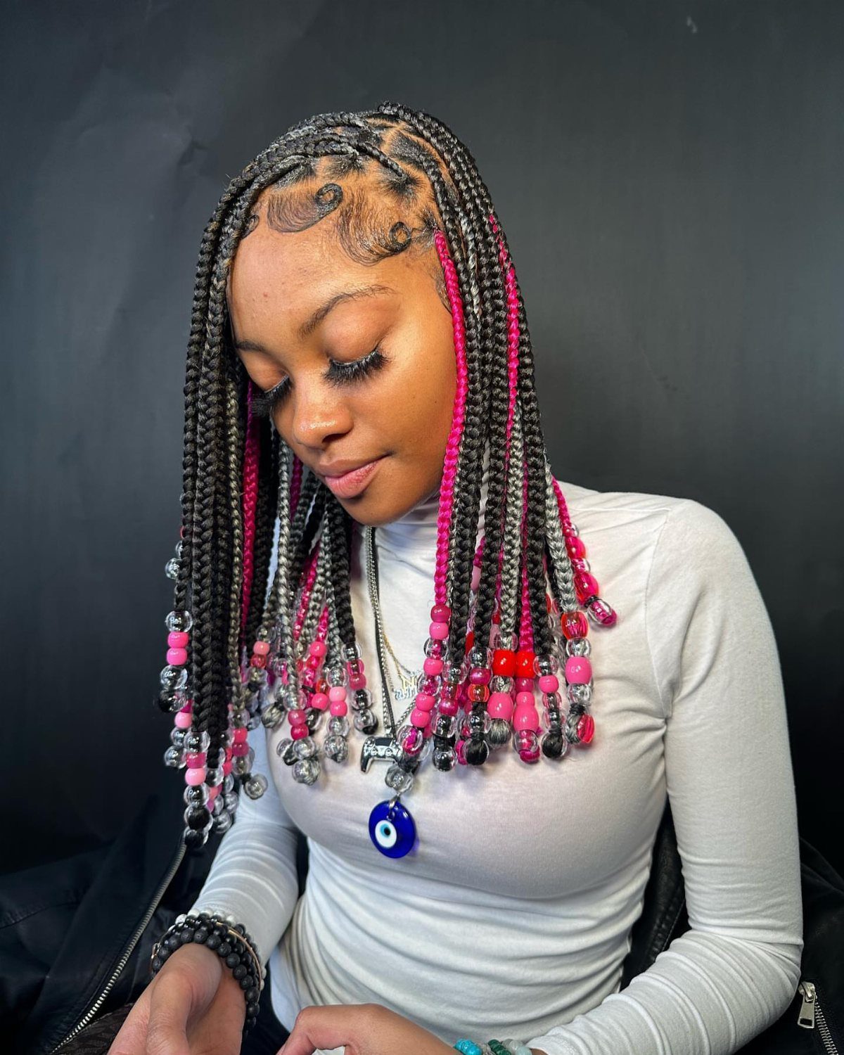 Woman with black and pink box braids decorated with colorful beads at the ends.